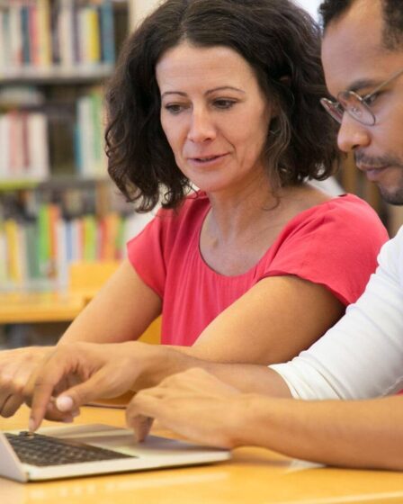 Dois estudantes analisando informações no notebook e tirando dúvidas sobre pós-graduação lato sensu e stricto sensu.