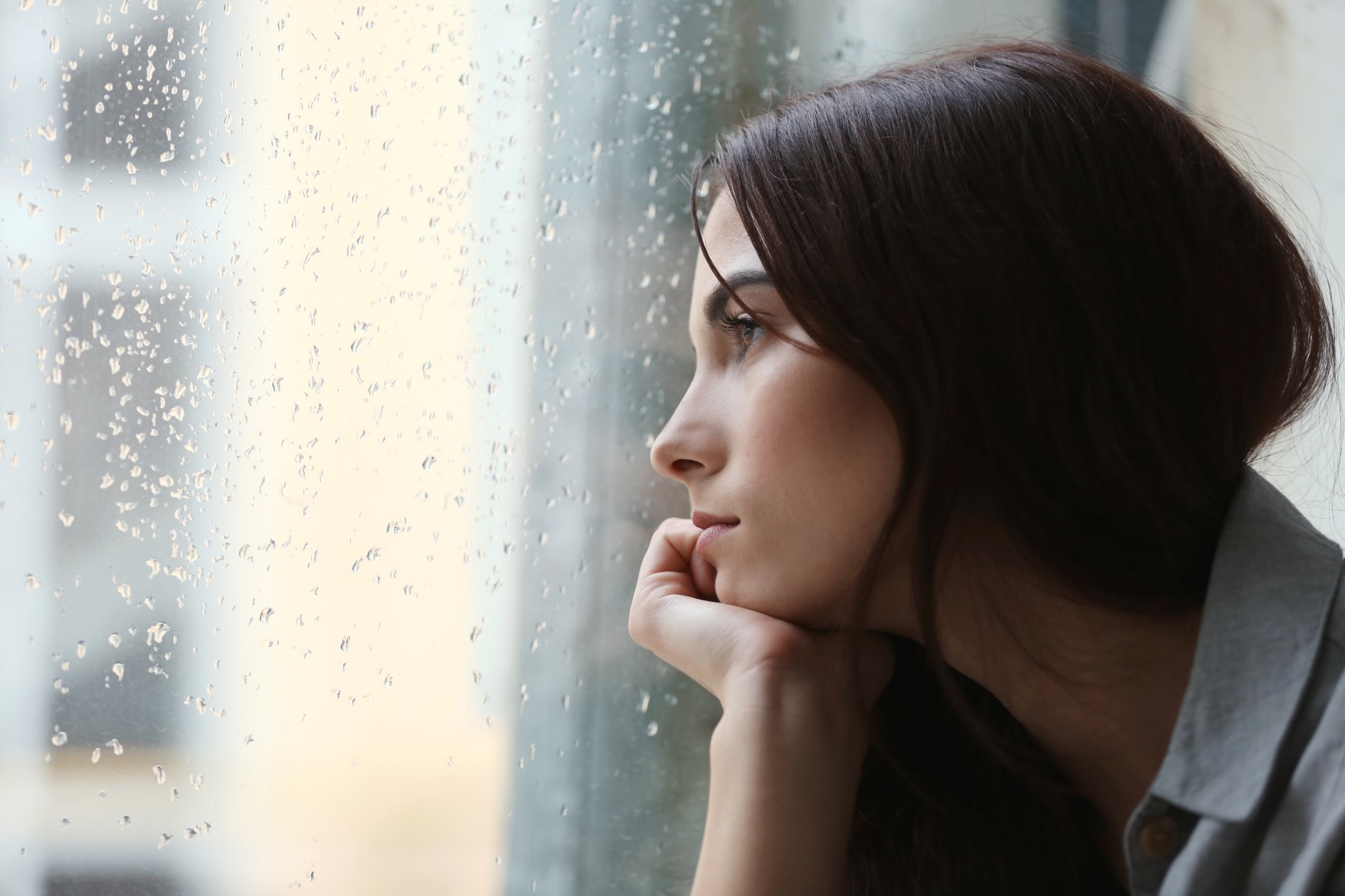 mulher olhando para a janela em um dia chuvoso