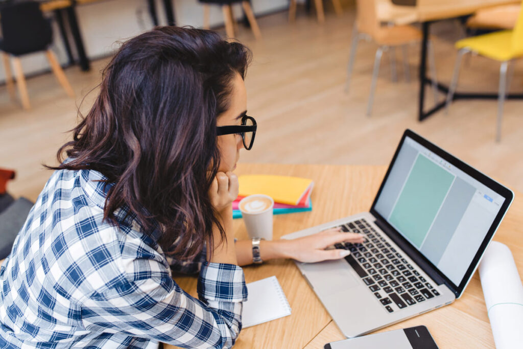 Mulher pesquisando no notebook informações sobre pós-graduação reconhecida pelo MEC.