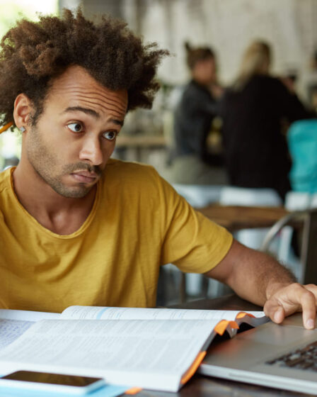Homem estudando com livro, lápis e notebook em um ambiente acadêmico, buscando informações sobre pós-graduação reconhecida pelo MEC.