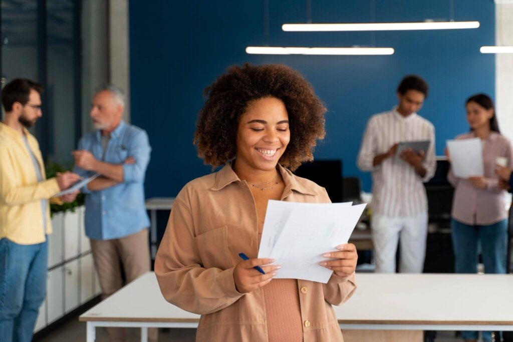 Jovem revisa documentos em ambiente corporativo, representando a preparação para o primeiro emprego e o desenvolvimento de carreira.