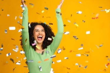 Imagem de uma mulher animada comemorando uma grande vitória, com confetes em fundo amarelo.