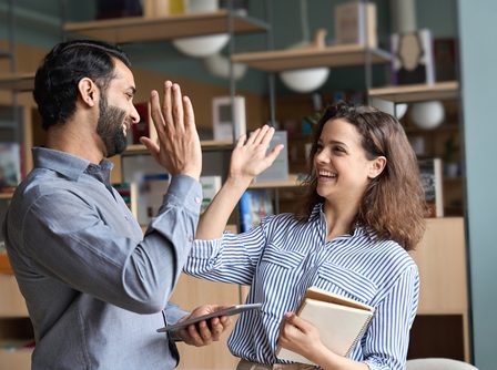 Dois professores felizes se cumprimentando em um ambiente de lazer localizado no trabalho deles.