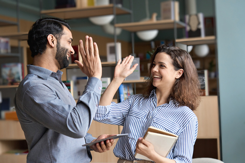 Dois professores felizes se cumprimentando em um ambiente de lazer localizado no trabalho deles.