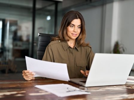 Imagem de uma mulher representando uma empresária em seu escritório em frente ao notebook.