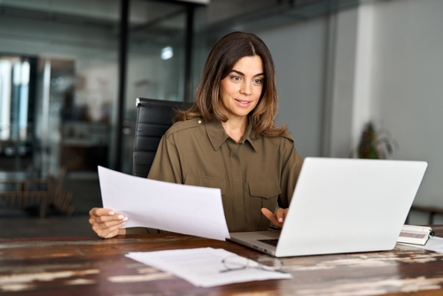 Imagem de uma mulher representando uma empresária em seu escritório em frente ao notebook.