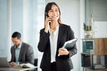 Dois juristas com roupas sociais, trabalhando em um escritório, um homem ao computador e uma mulher ao celular.