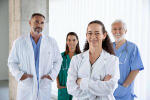 Equipe médica com quatro profissionais em hospital, incluindo médicos e enfermeiros, representando diferentes profissões na área da saúde.