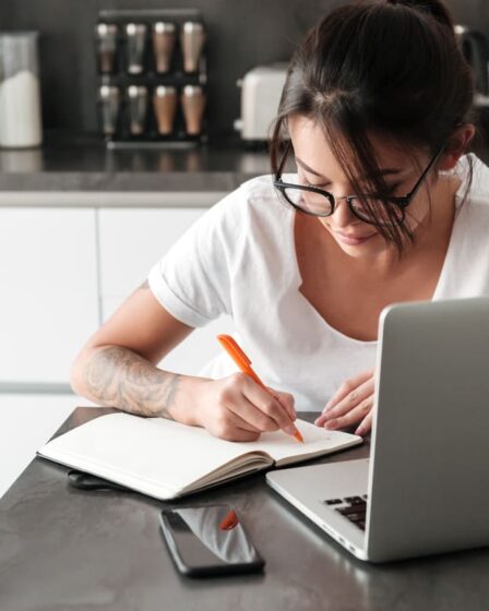 Mulher estudando com notebook e fazendo anotações em um caderno