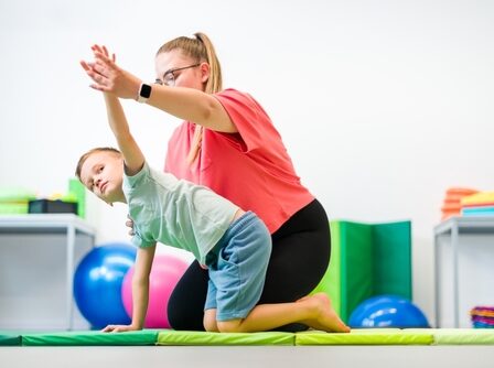 Criança praticando exercícios de reabilitação com apoio de uma terapeuta ocupacional.