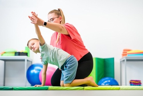 Criança praticando exercícios de reabilitação com apoio de uma terapeuta ocupacional.
