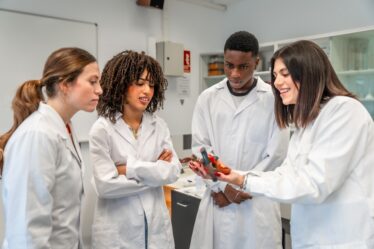 Professora segura um modelo anatômico de coração, enquanto o mostra para alunos em um laboratório universitário.