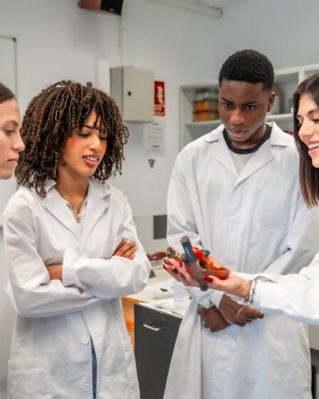 Professora segura um modelo anatômico de coração, enquanto o mostra para alunos em um laboratório universitário.