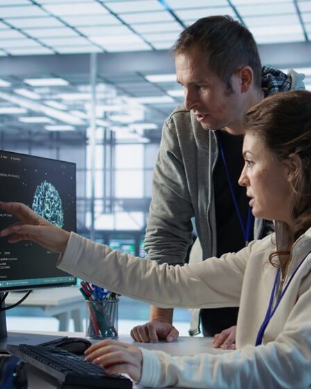 Profissionais de TI observam informações me monitor enquanto um deles aponta para a tela.