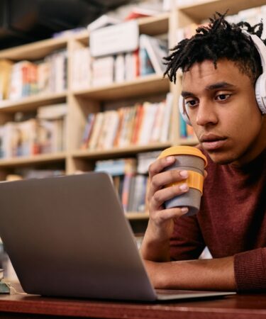 Estudante estudando online em um computador na biblioteca.