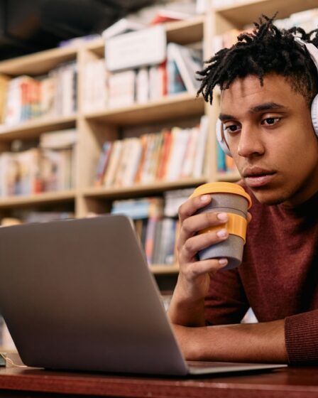 Estudante estudando online em um computador na biblioteca.