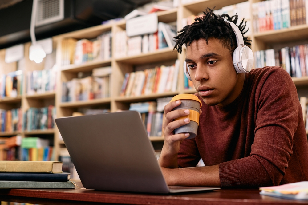 Estudante estudando online em um computador na biblioteca.