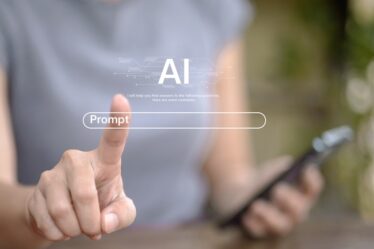 Imagem embaçada ilustrando uma pessoa com um celular na mão e simulando um touch screem na dela como se escrevesse um prompt.