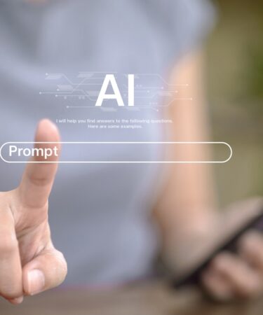 Imagem embaçada ilustrando uma pessoa com um celular na mão e simulando um touch screem na dela como se escrevesse um prompt.