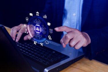 Homem sentado mexe no notebook e aponta para uma ilustração de uma interface de inteligência artificial