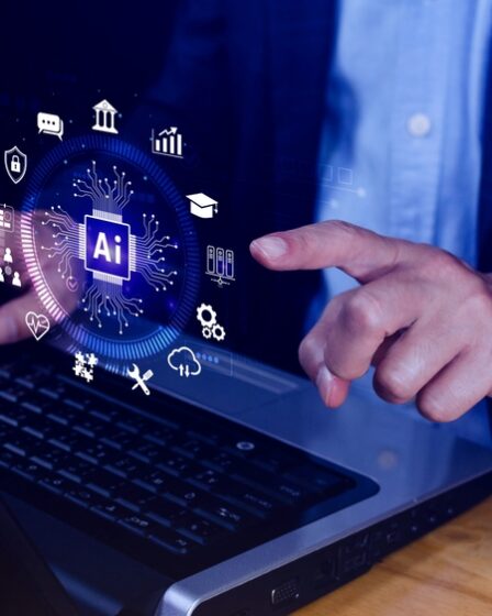 Homem sentado mexe no notebook e aponta para uma ilustração de uma interface de inteligência artificial