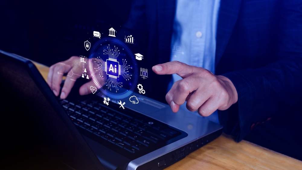 Homem sentado mexe no notebook e aponta para uma ilustração de uma interface de inteligência artificial