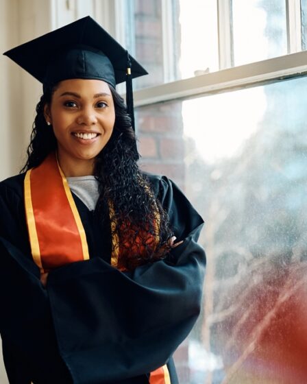 Estudante afro-americana de pós-graduação, feliz, em pé com os braços cruzados e olhando para a câmera.