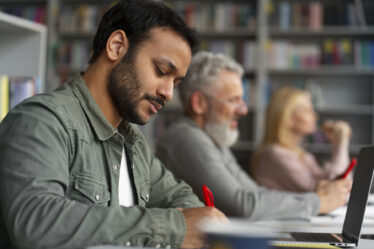 Homem adulto escrevendo em sala de aula, representando foco e aprendizado no contexto de o que é EJA e educação continuada.