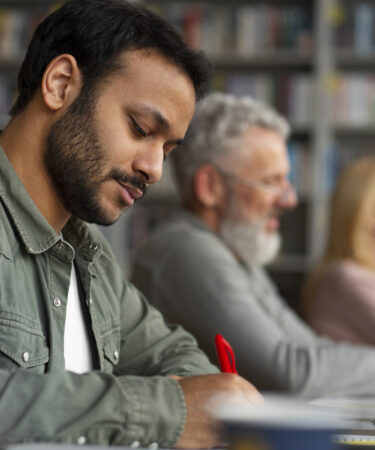 Homem adulto escrevendo em sala de aula, representando foco e aprendizado no contexto de o que é EJA e educação continuada.