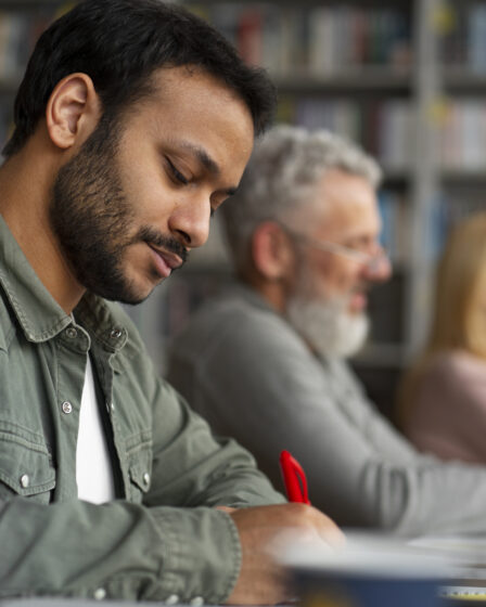 Homem adulto escrevendo em sala de aula, representando foco e aprendizado no contexto de o que é EJA e educação continuada.