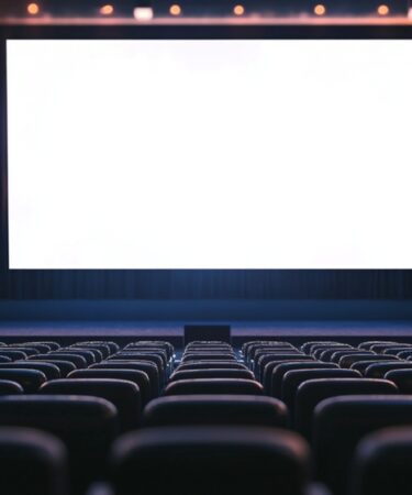 Imagem de uma sala de cinema completamente vazia vista da parte de trás, como se fosse a visão do projetor.