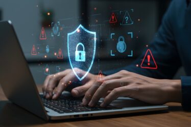 Feche as mãos digitando no laptop com holograma de escudo digital, proteção de segurança cibernética, defesa de firewall, privacidade de dados on-line e interface de alertas de advertência de segurança da Internet.