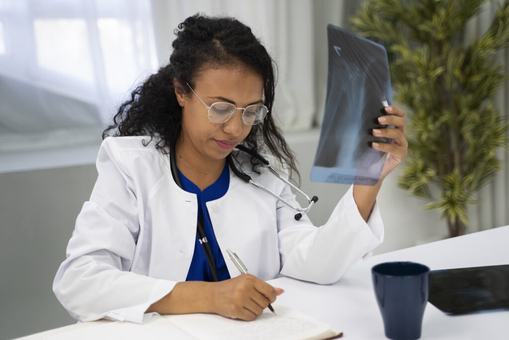 Médica analisando um exame de raio-x enquanto faz anotações, em uma cena que representa o aprendizado prático em um curso de Radiologia.