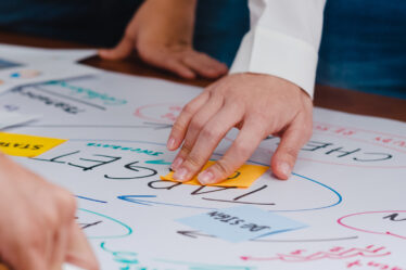 Grupo organizando ideias com post-its e palavras-chave em papel, exemplo prático de como fazer um mapa mental colaborativo