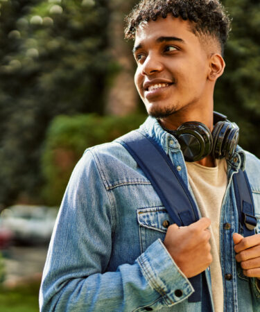 Estudante com mochila e fones de ouvido caminhando no campus, representando como funciona o Prouni para ingressar na universidade.