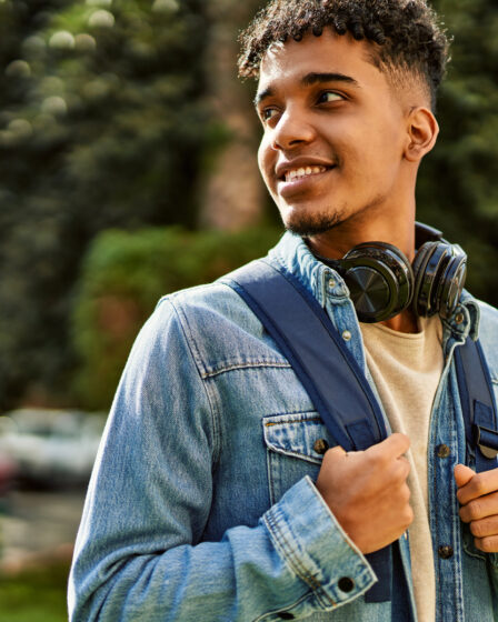 Estudante com mochila e fones de ouvido caminhando no campus, representando como funciona o Prouni para ingressar na universidade.