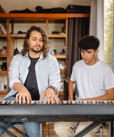 Professor de música tocando piano com aluno