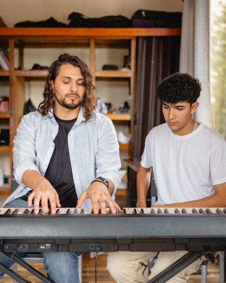 Professor de música tocando piano com aluno