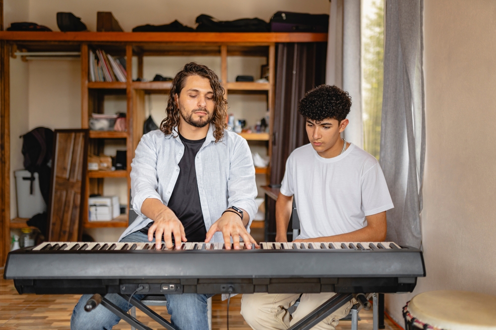 Professor de música tocando piano com aluno