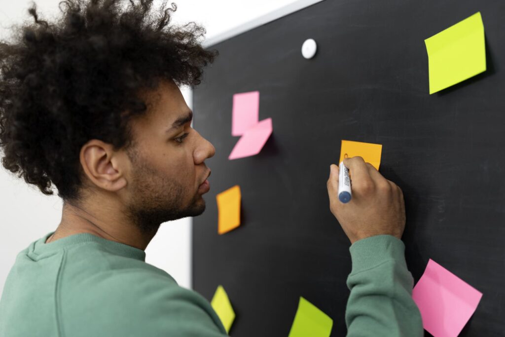 Homem escrevendo em um post-it durante uma atividade de planejamento sobre o que é PDI.