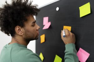 Homem escrevendo em um post-it durante uma atividade de planejamento sobre o que é PDI.