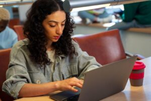 Mulher utilizando um notebook ao concluir sua pesquisa sobre o que é ABNT para finalizar seus estudos.