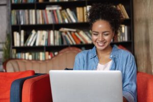 Mulher jovem concentrada ao digitar em um notebook, pesquisando o que é ABNT para formatar seu trabalho acadêmico.