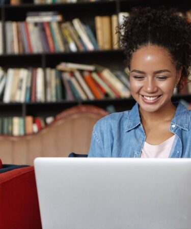 Mulher jovem concentrada ao digitar em um notebook, pesquisando o que é ABNT para formatar seu trabalho acadêmico.