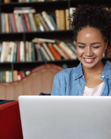 Mulher jovem concentrada ao digitar em um notebook, pesquisando o que é ABNT para formatar seu trabalho acadêmico.