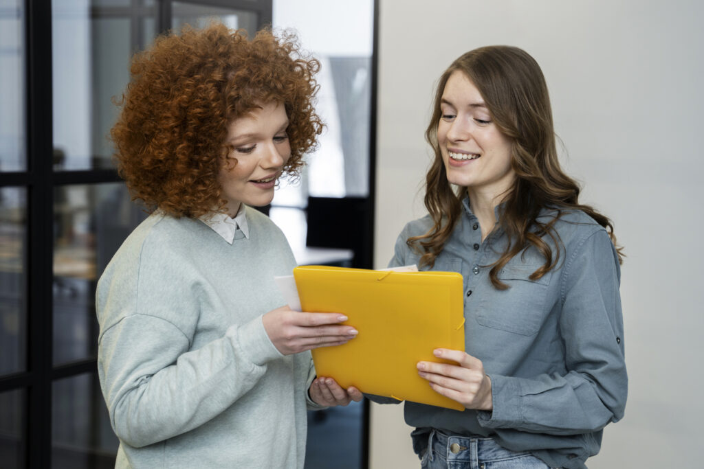 Profissionais em ambiente de escritório analisam documentos, demonstrando comunicação assertiva durante colaboração em equipe.