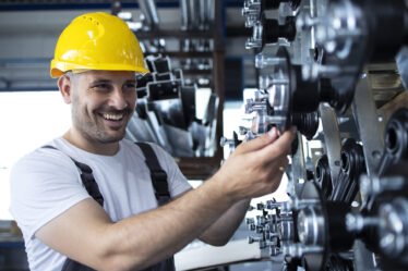 Profissional trabalhando em uma máquina industrial, representando as habilidades desenvolvidas na faculdade de Engenharia Mecânica.