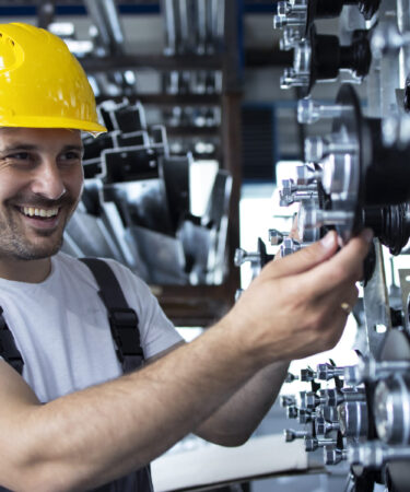 Profissional trabalhando em uma máquina industrial, representando as habilidades desenvolvidas na faculdade de Engenharia Mecânica.