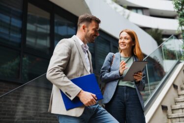 Dois colegas de negócios tendo uma discussão profissional fora de um prédio de escritórios.