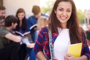 Mulher jovem em um ambiente universitário, com outros estudantes ao fundo, representando a rotina acadêmica da Uninter. 